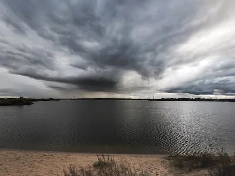 A dramatic view of the lake above which a dark cloud has formed. Stock Photos