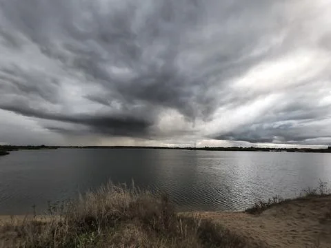 A dramatic view of the lake above which a dark cloud has formed. Stock Photos