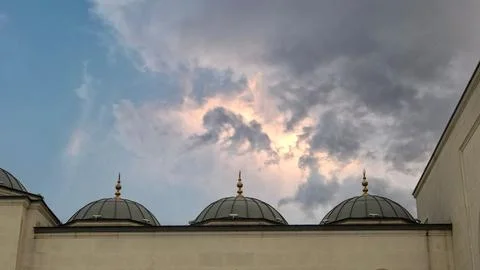 Dramatic view of mosque domes under a stormy sky with golden finials at dusk Stock Photos
