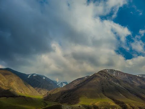 Dramatic view of mountains in serene valley with stormy clouds above Stockfoto's