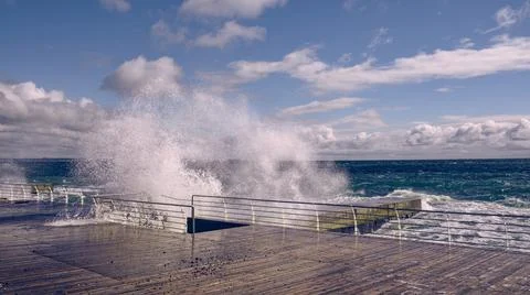 Dramatic view of sea waves crashing against the concrete pier Stock Photos