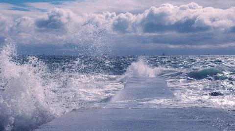 Dramatic view of sea waves crashing against the concrete pier Stock Photos