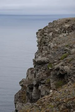 Dramatic view of steep, dark cliffs and rocky coastline at Nordkapp rising ab Stock Photos