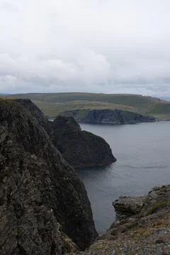Dramatic view of steep, dark cliffs and rocky coastline at Nordkapp rising ab Stock Photos