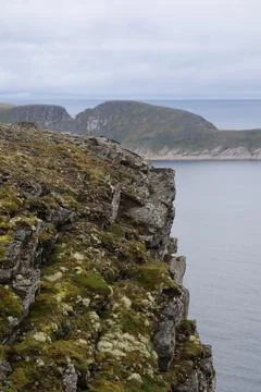 Dramatic view of steep, dark cliffs and rocky coastline at Nordkapp rising ab Stock Photos