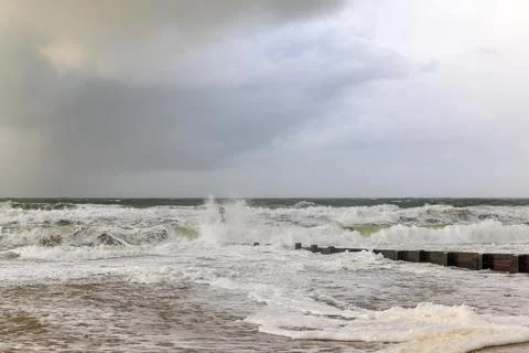 A dramatic view of a very choppy sea with huge crashing waves on groynes (bre Stock Photos
