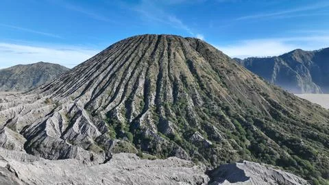 A dramatic view of a volcanic cone with deep vertical ridges carved by erosion Fotos Stock