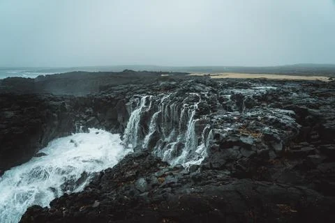 Dramatic Volcanic Coastline with Ocean Waves and Dark Basalt Cliffs in Icelan Stock Photos