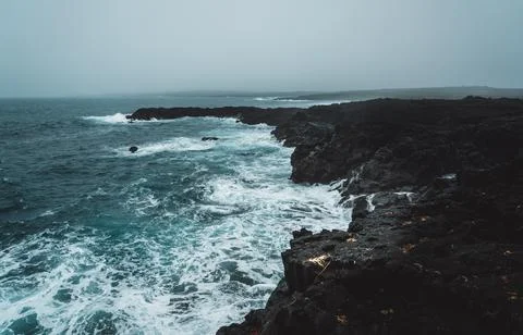Dramatic Volcanic Coastline with Ocean Waves and Dark Basalt Cliffs in Icelan Stock Photos