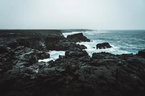 Dramatic Volcanic Coastline with Ocean Waves and Dark Basalt Cliffs in Icelan Stock Photos