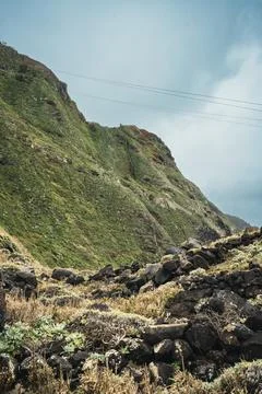 Dramatic Volcanic Landscape with Lush Green Mountain Slope and Rocky Foregr.. Stock Photos
