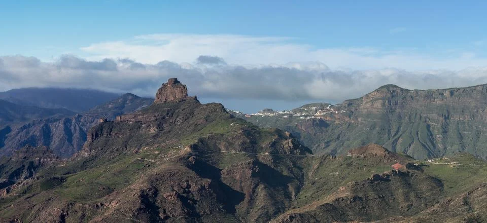 Dramatic volcanic mountain landscape with distant village Stock Photos