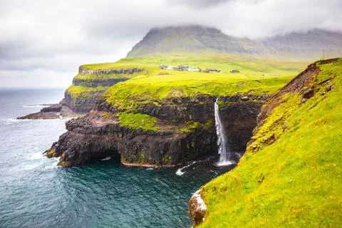 Dramatic waterfall on Faroe Islands and the village Gasadalur Stock Photos