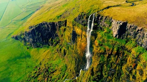Dramatic waterfall plunges down lush green cliffside on a bright sunny day. Stock Footage 343695834