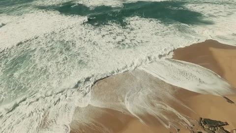 Dramatic waves crash against rugged cliffs and sandy shores Stock Footage 341823896
