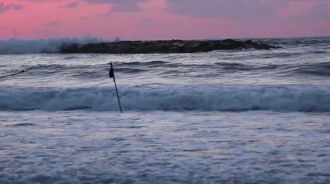 Dramatic waves in the sunset seen from shore, a man's silhouette walks through Stock Footage 66688769