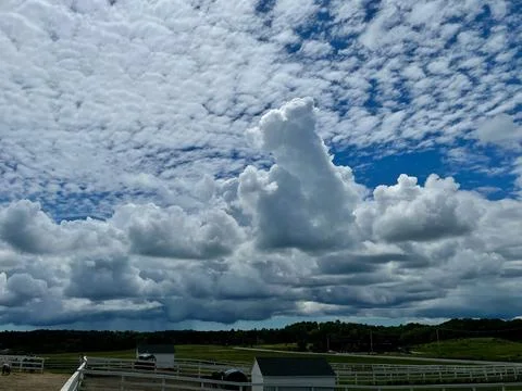 Dramatic white and dark clouds thrusting up into the sky over land Stock Photos