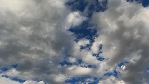 Dramatic white and gray clouds float across the blue sky. Timelapse. Video stock 238526930