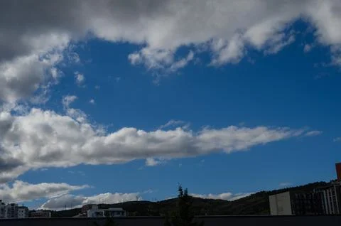 Dramatic white clouds and patches of blue sky over urban buildings in Tbili.. Stock Photos
