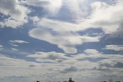 Dramatic white clouds spread across blue sky above a distant urban horizon Stock Photos