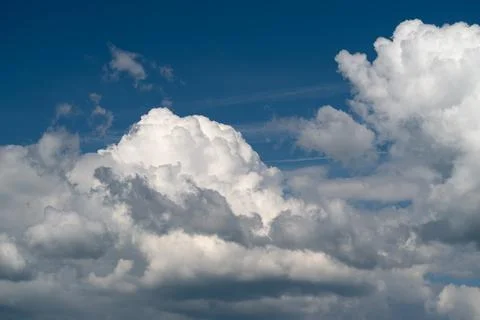 Dramatic white cumulus clouds against deep blue sky Stock Photos