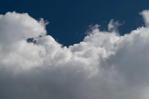 Dramatic white cumulus clouds against deep blue sky Stock Photos