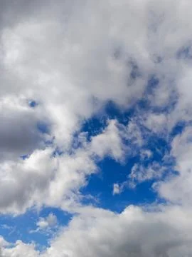 Dramatic white cumulus clouds breaking to reveal bright blue sky Stock Photos