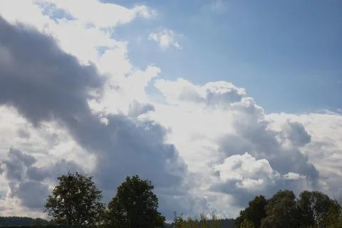 Dramatic white cumulus clouds drifting across a bright blue sky above a lin.. Stock Photos