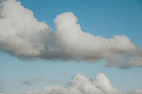 Dramatic white cumulus clouds floating across a clear blue sky with layered.. Stock Photos