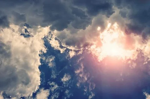 Dramatic white fluffy clouds with sun rays. A horizontal frame. Stock Photos