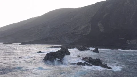 Dramatic white waves smashing rocky volcanic shoreline, exposing rugged coastal Stock Footage 308403903