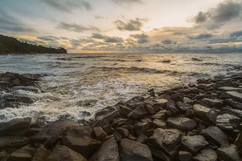 A dramatic wide-angle shot of a rocky breakwater at sunset Stock Photos