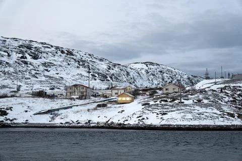A dramatic wide angle view of black lava pebble beach with snow. Arctic Ocean Photos
