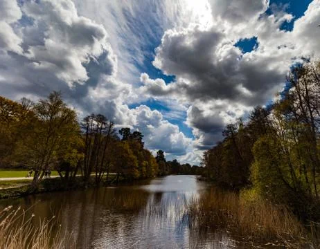 Dramatic wide angle view of a river surrounded by trees, cloudy, stormy sky Stock Photos