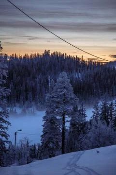 Dramatic winter sunset over snowy Scandinavian mountain forest Stock Photos
