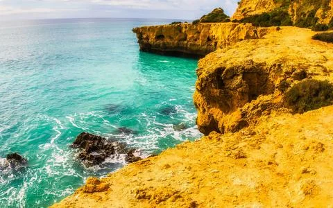 Dramatic yellow cliffs meet turquoise ocean waters under a cloudy sky provi.. Photos