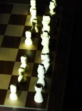 Dramatically lit chess pieces on a board Stock Photos
