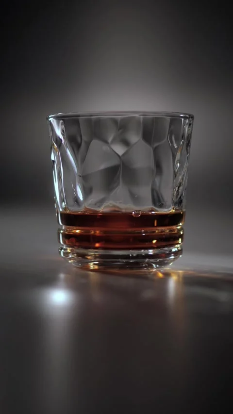 Dramatically lit glass of whiskey on a table in a dark atmosphere. Stock Footage 337242024