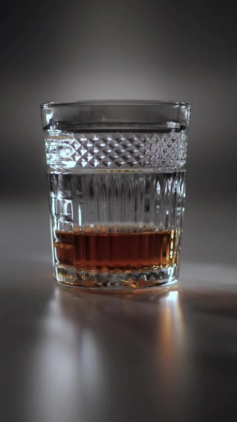 Dramatically lit glass of whiskey on a table in a dark atmosphere. Stock Footage 337242031
