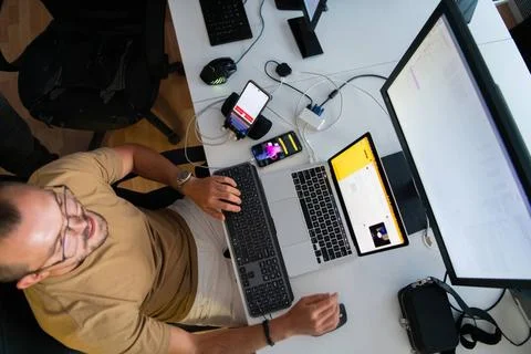 Draufsicht auf einen Programmierer, der in seinem Büro sitzt und fleißig S. Stock-Fotos