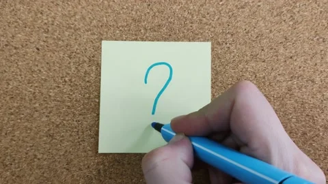 Draw a question mark with a blue felt-tip pen on a yellow paper sticker Video stock 172012431