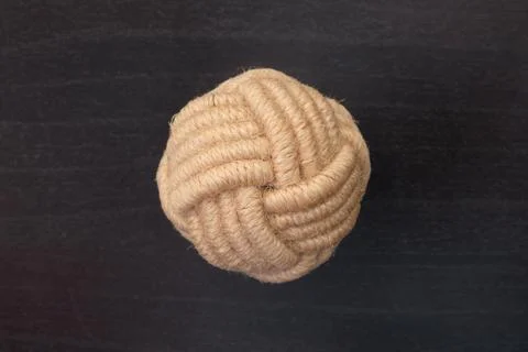 Drawer pull handle wrapped in natural beige rope on dark wooden surface. Stud Stock Photos