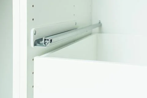 Drawer rail inserted into cabinet, fixed with self-tapping screws. Assembling Stock Photos
