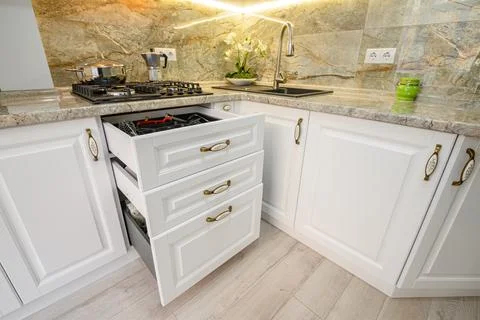 Drawers pulled out at modern classic white kitchen furniture Stock Photos