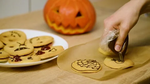 Drawing a chocolate spider character on a baked shortbread cookie Stock Footage 342704275