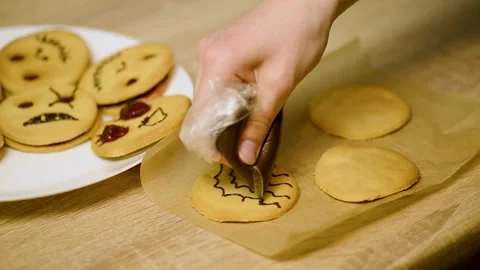 Drawing a chocolate spiderweb pattern on a round holiday cookie Stock Footage 342704242