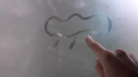 Drawing of cloud and rain symbol drawn with finger on foggy glass. Stock Footage 261189708