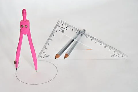 A drawing compass and a triangular ruler with two pencils in the middle of th Stock Photos