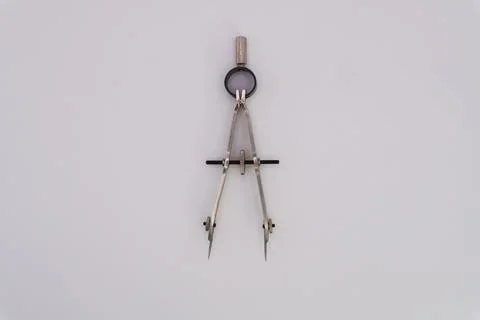 Drawing compass on a white background made of silver-colored metal Stock Photos