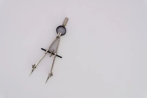Drawing compass on a white background made of silver-colored metal Stock Photos